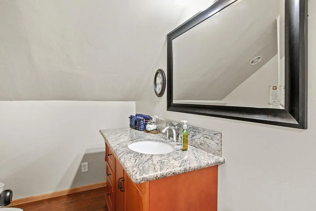 Upper bathroom with a granite single vanity under the eaves
