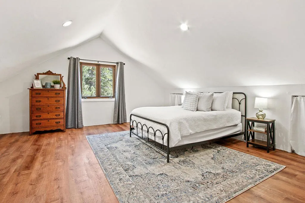 Upper bedroom with an iron bed and antique dresser under the eaves
