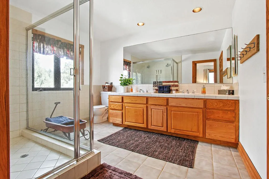 Bathroom with a long oak double vanity and glass shower