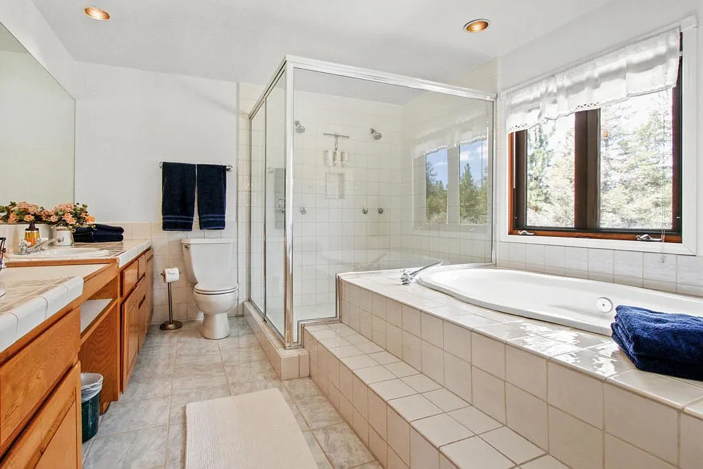 Bathroom with a tiled soaking tub by the window and a glass shower