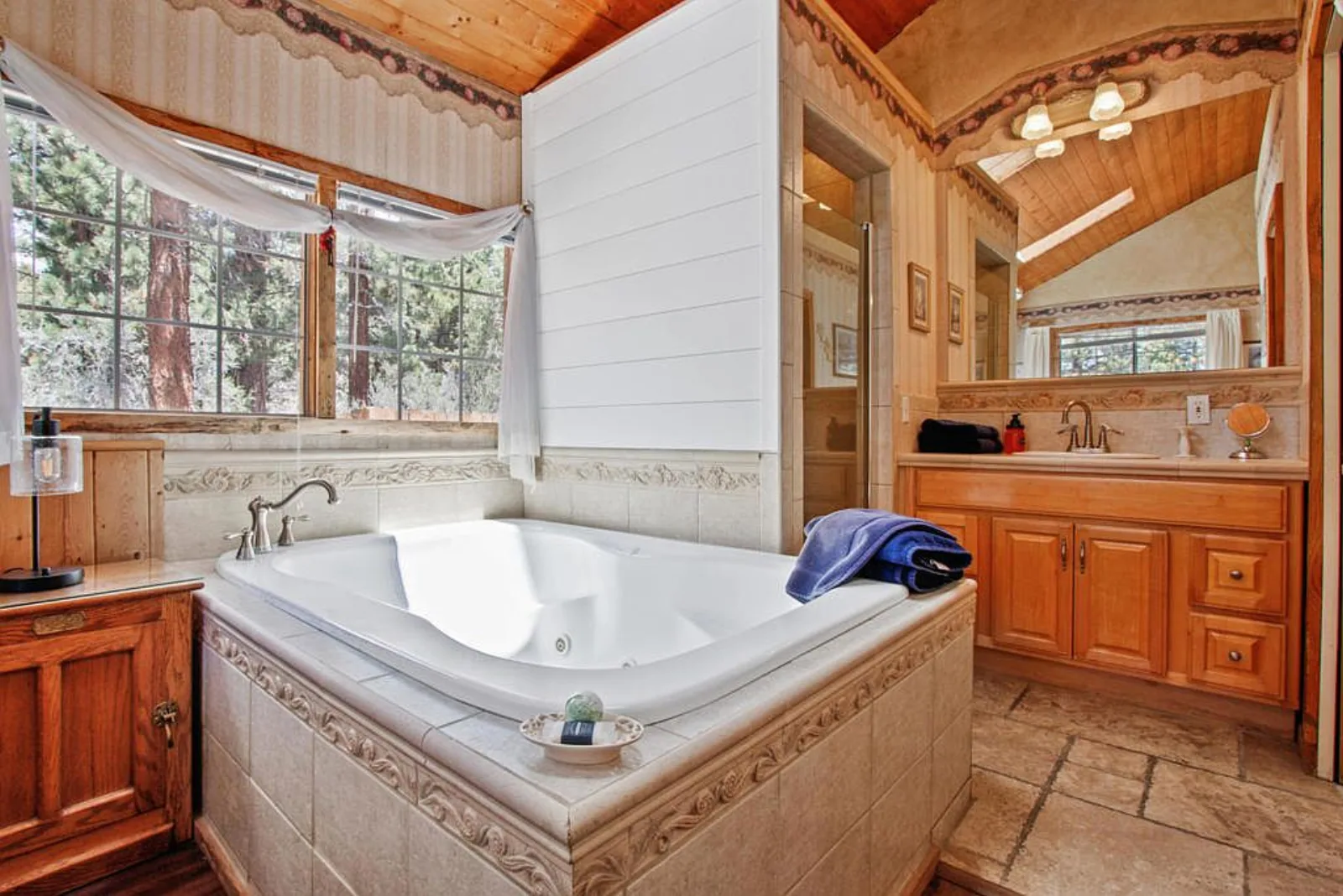Bathroom with a large tiled jetted tub under a wood plank ceiling