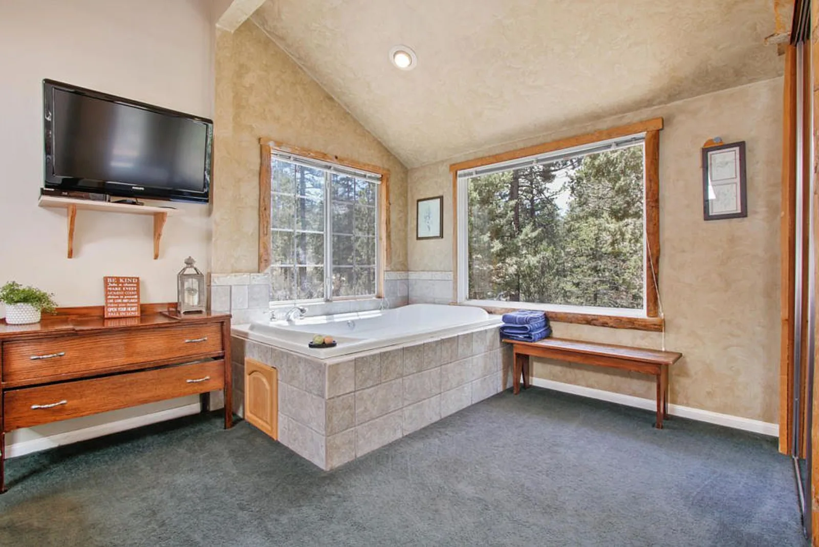 Jetted tub set beside forest view windows