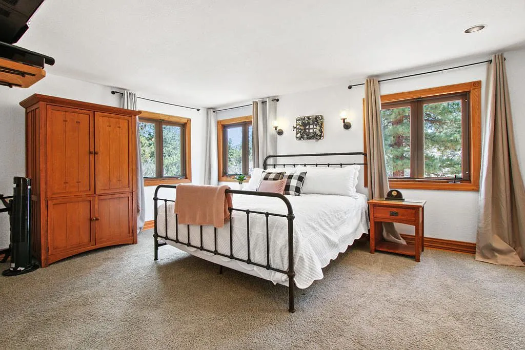 Bright bedroom with a black iron bed and a wooden armoire