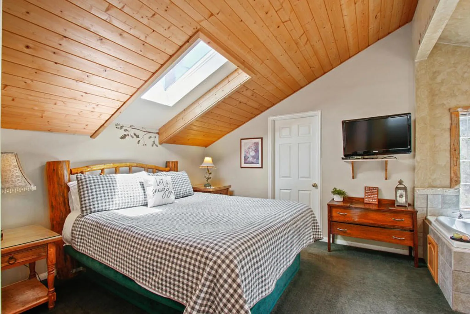 Bedroom with a log frame bed under a skylit knotty pine ceiling