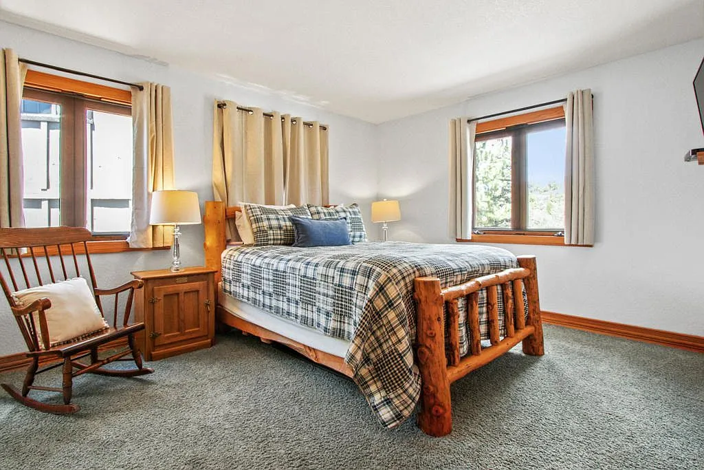 Bedroom with a log frame bed, plaid comforter and a rocking chair