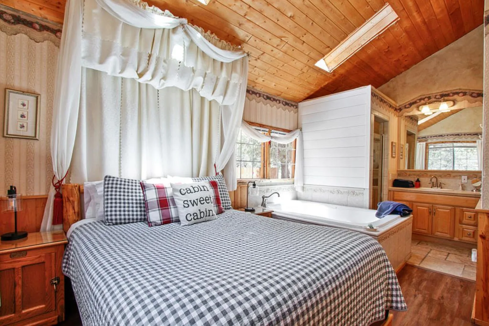 Cabin bedroom with a canopy bed, skylight and jetted tub alongside