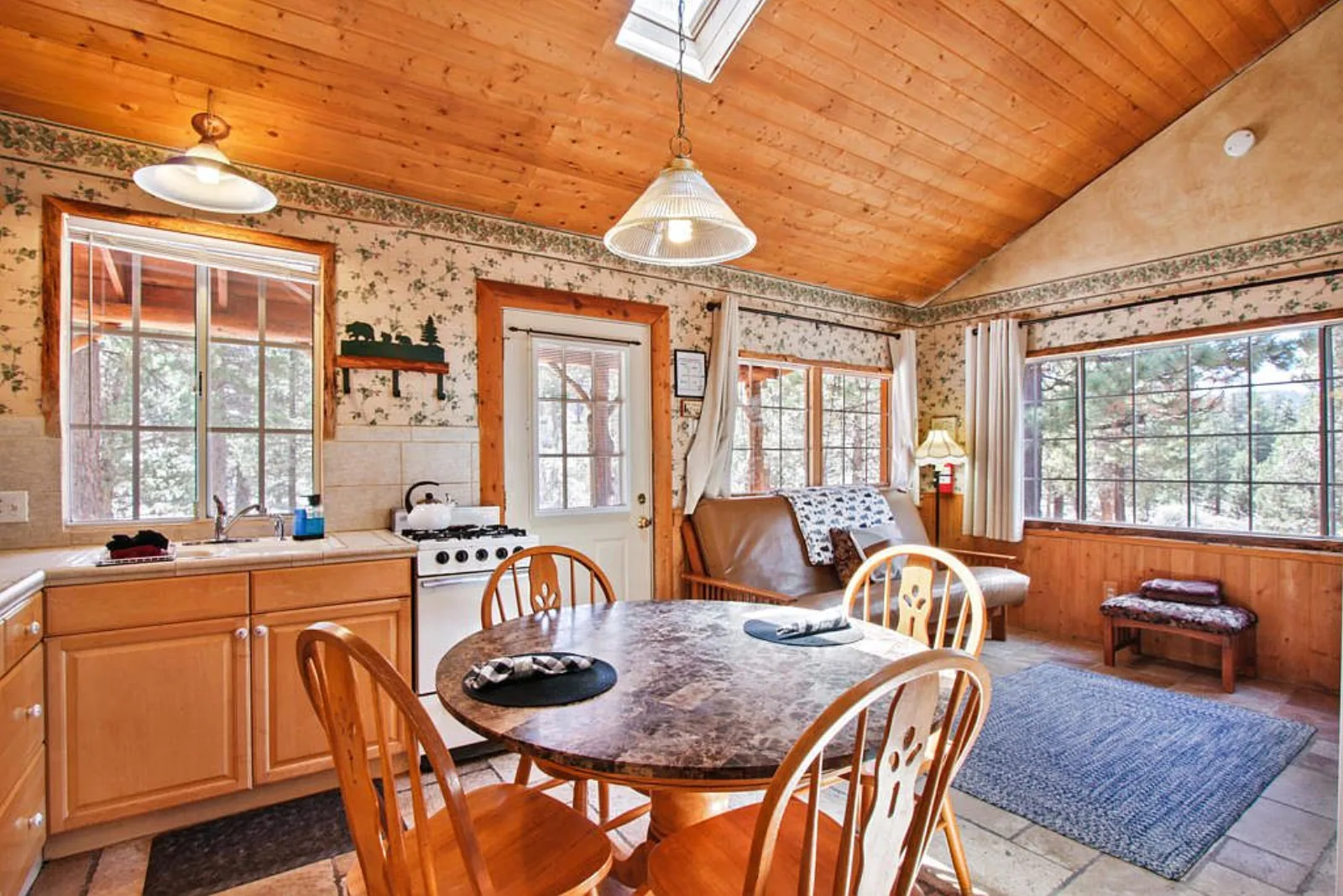 Cabin kitchen and dining under a skylit wood plank ceiling