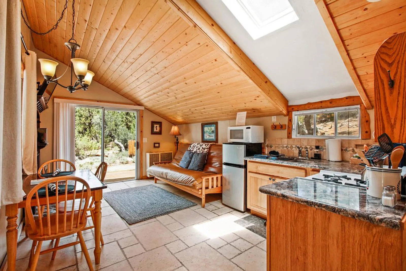 Cabin open plan living area with a skylit wood ceiling, kitchenette and slider to the deck