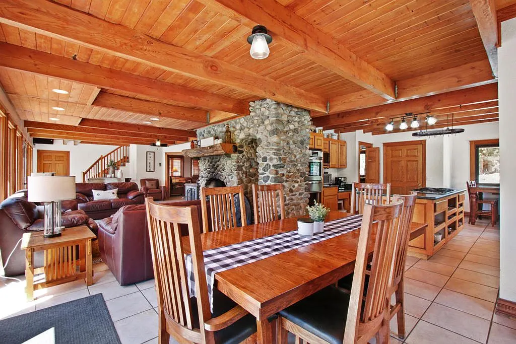 Long dining table open to the kitchen and stone fireplace