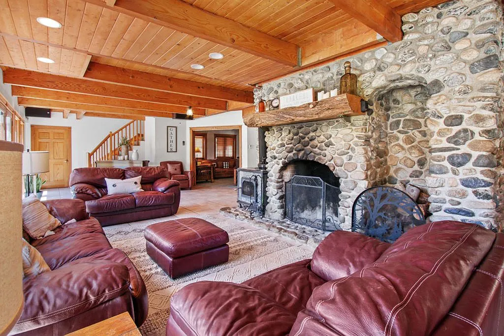 Lodge great room with its river rock fireplace, wood stove and leather sofas