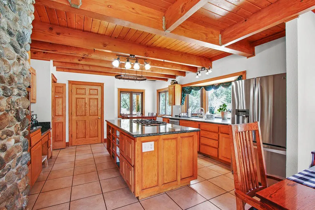Lodge kitchen with a granite island and gas cooktop beside the stone chimney
