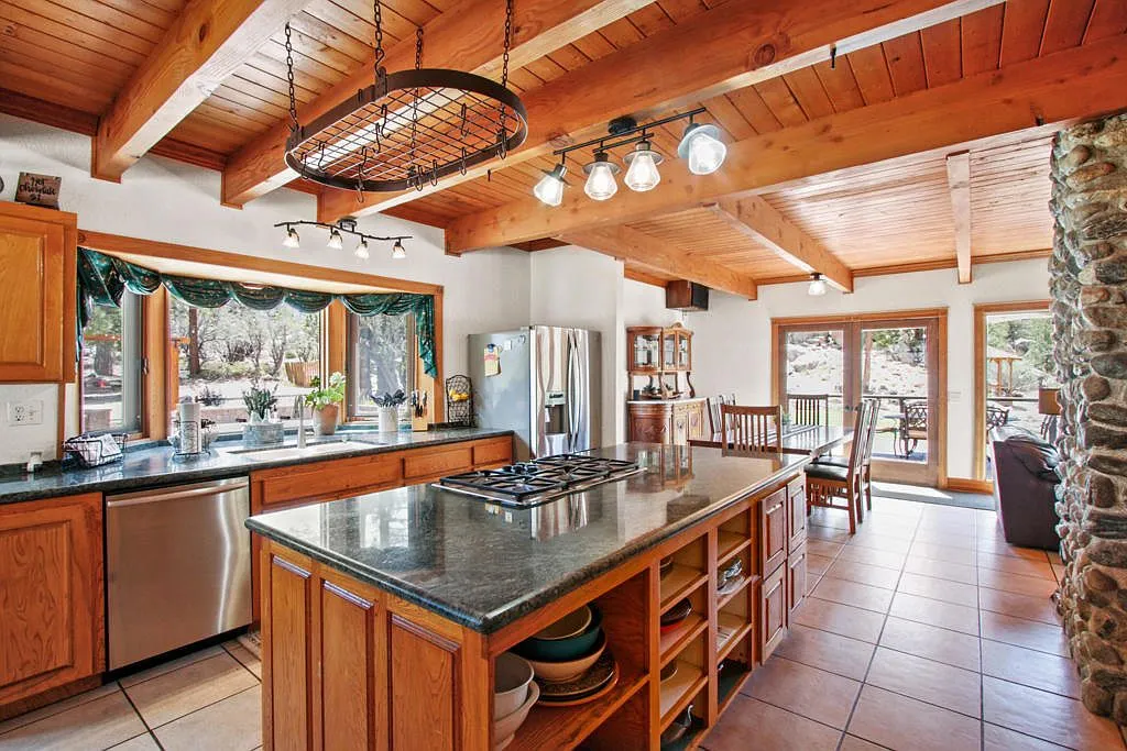Lodge kitchen with a granite island, pot rack and French doors to the deck