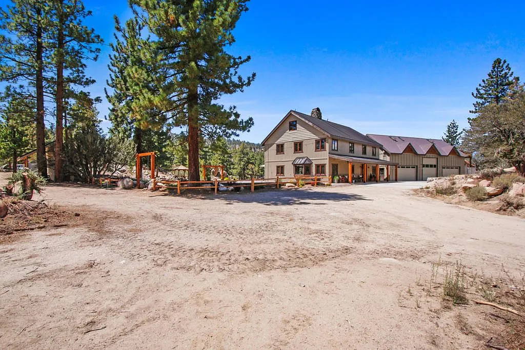 The Lodge and garage bays seen from the dirt drive through tall pines