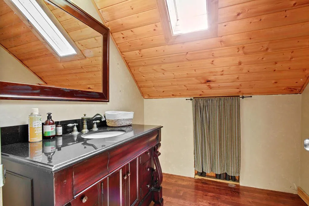Loft bathroom with a dark wood vanity beneath a skylight