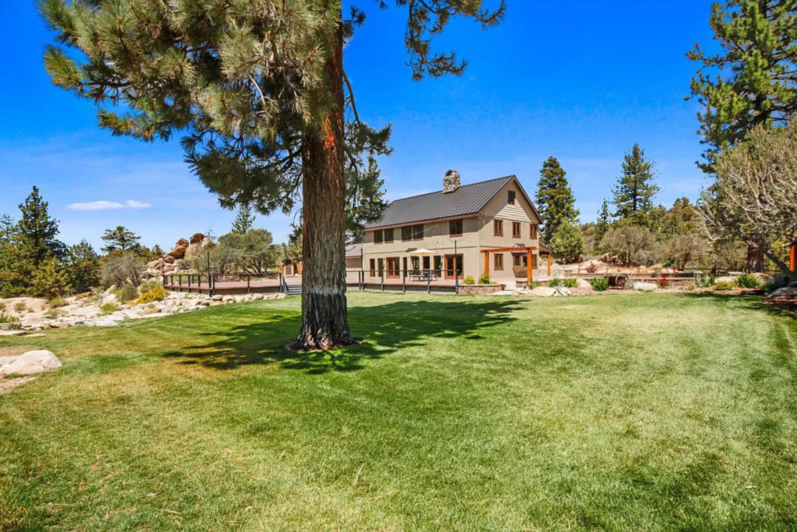 Expansive green lawn framed by a mature pine, with the main Sunstone Lodge behind