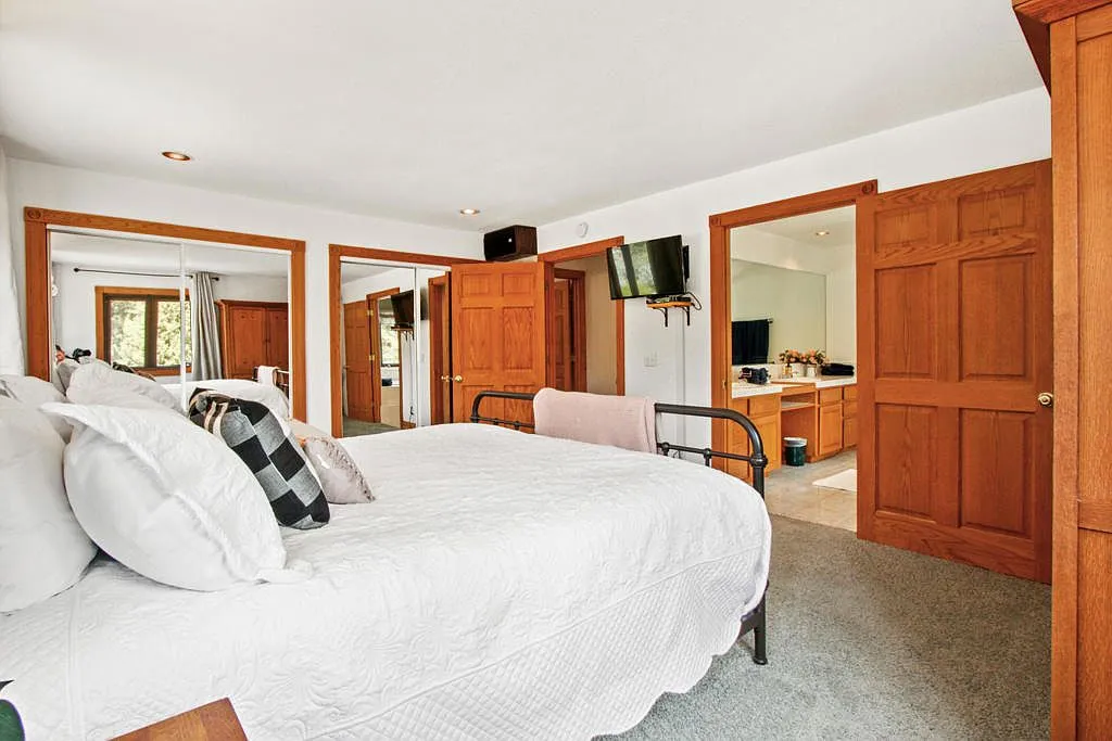 Main bedroom with white bedding and an ensuite bath through oak doors