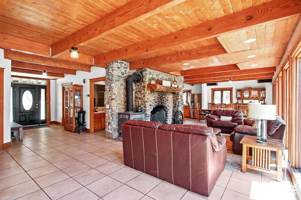 Open great room with the stone fireplace and beamed ceiling