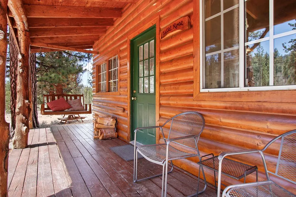 Wild Rose cabin porch with its name plaque, green door, swing and chairs